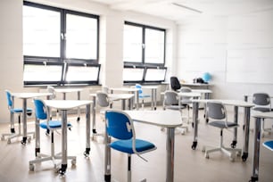 Desks in unconventional classoom, interior of private school.