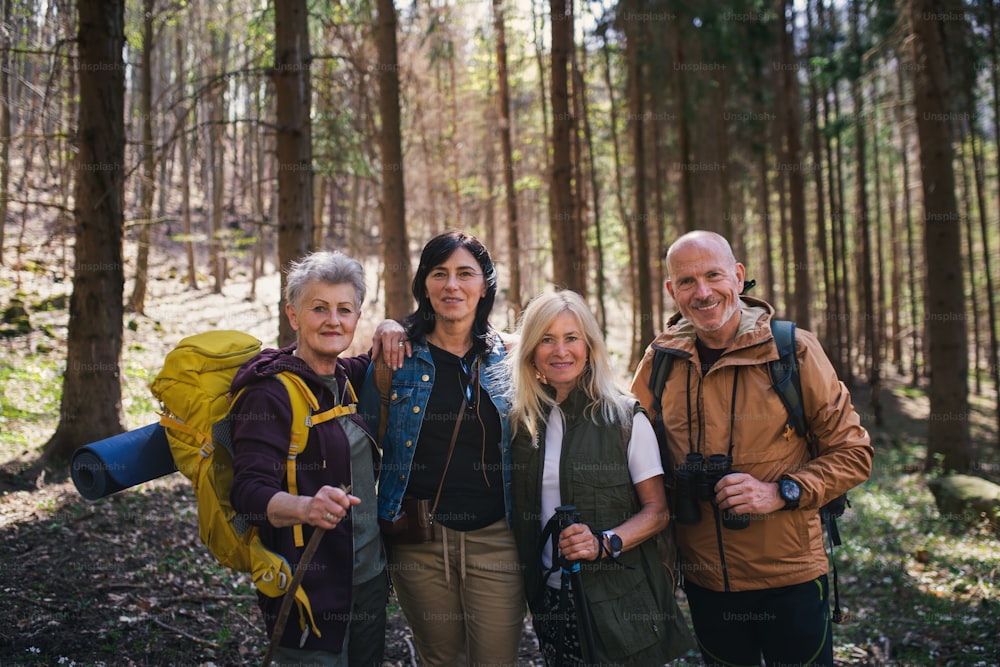 カメラを見ながら、自然の森の中で屋外の高齢者ハイカーのグループの肖像画。