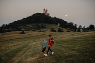 田舎の夕暮れ時に手をつないで走る若いカップルの正面図。