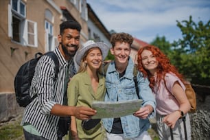 Un portrait d’un groupe de jeunes à l’extérieur en voyage en ville, à l’aide d’une carte.