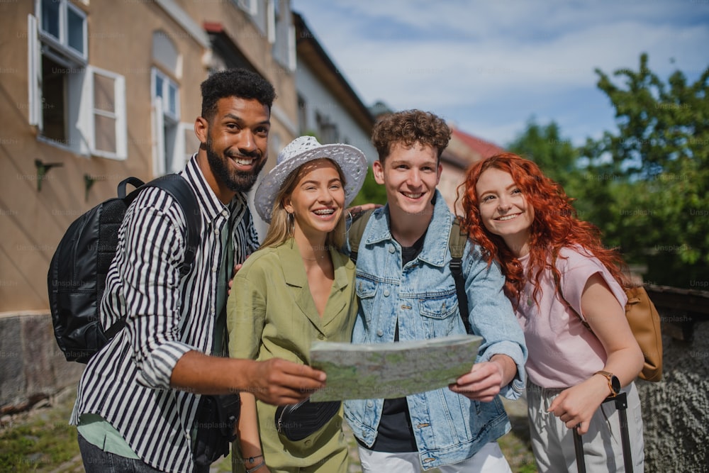 Un retrato de un grupo de jóvenes al aire libre en viaje en la ciudad, usando un mapa.