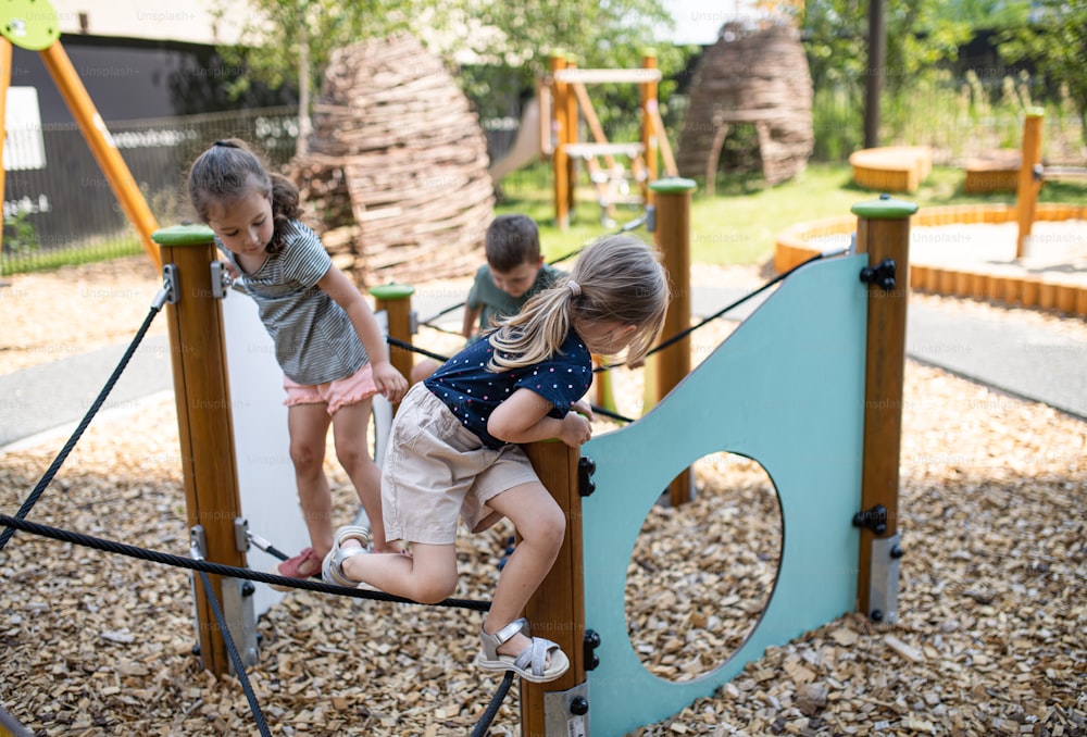 Un groupe de petits enfants de maternelle jouant à l’extérieur sur une aire de jeux.
