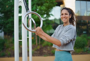 Mid adult woman doing exercise on a mat outdoors in city workout park, healthy lifestyle concept.