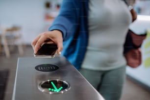 Female hand using a smartphone to open automatic gate machine in gym