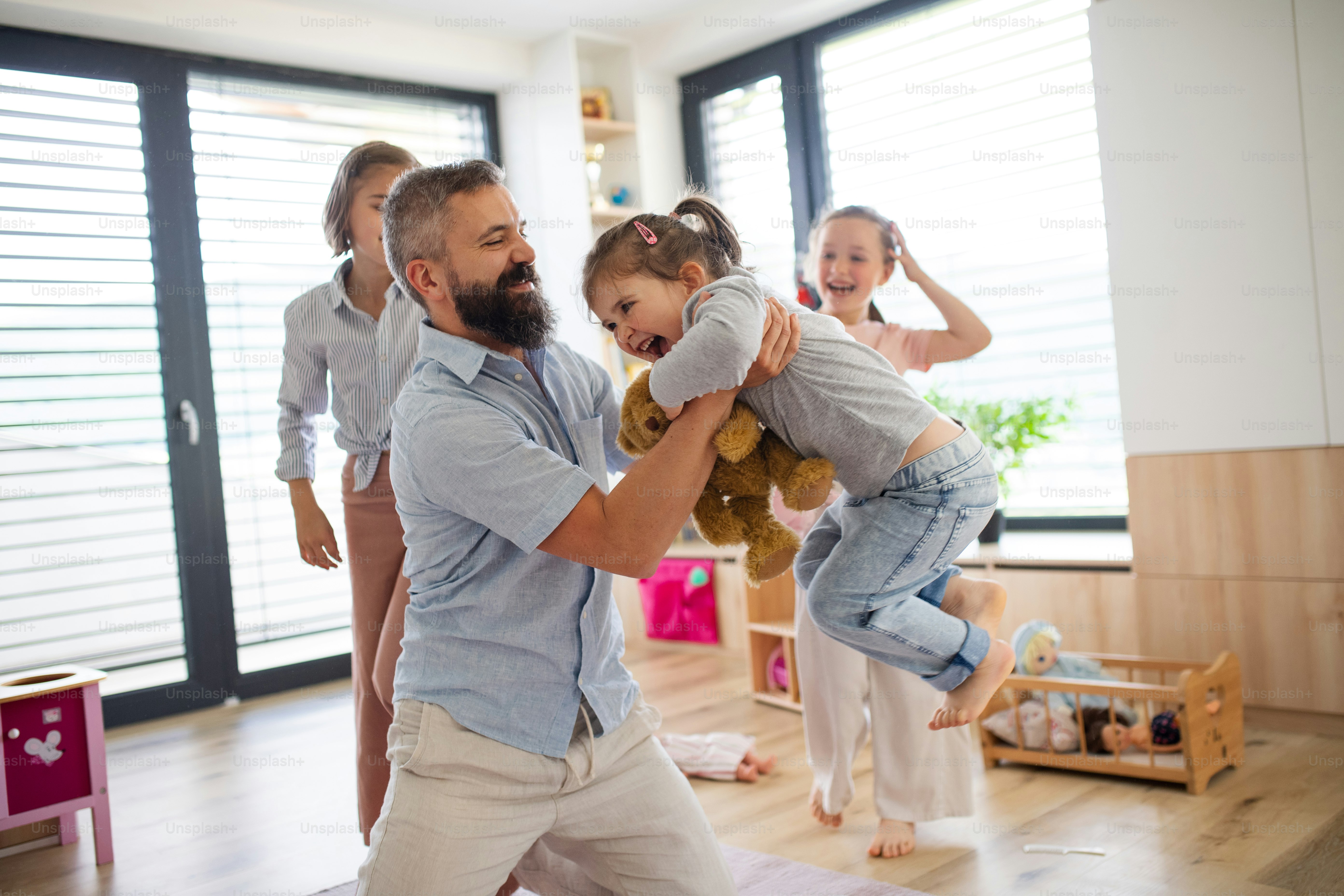 A father with three daughters indoors at home, playing on floor