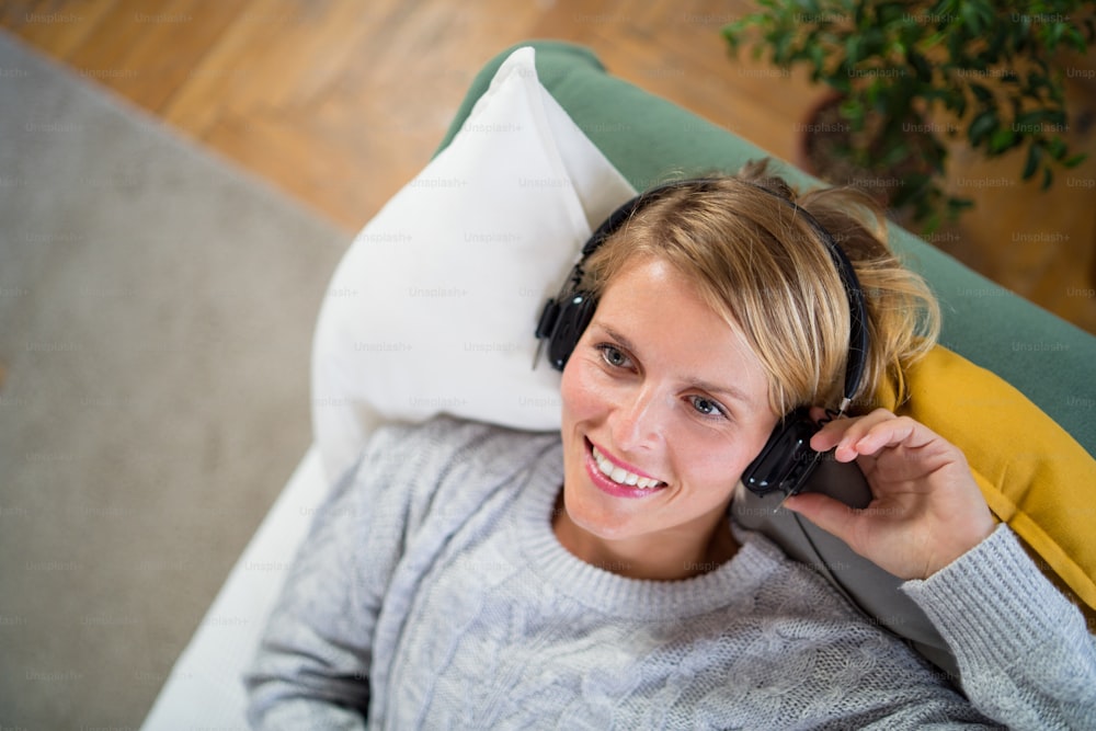 Top view portrait of woman with headphones relaxing indoors at home, mental health care concept.
