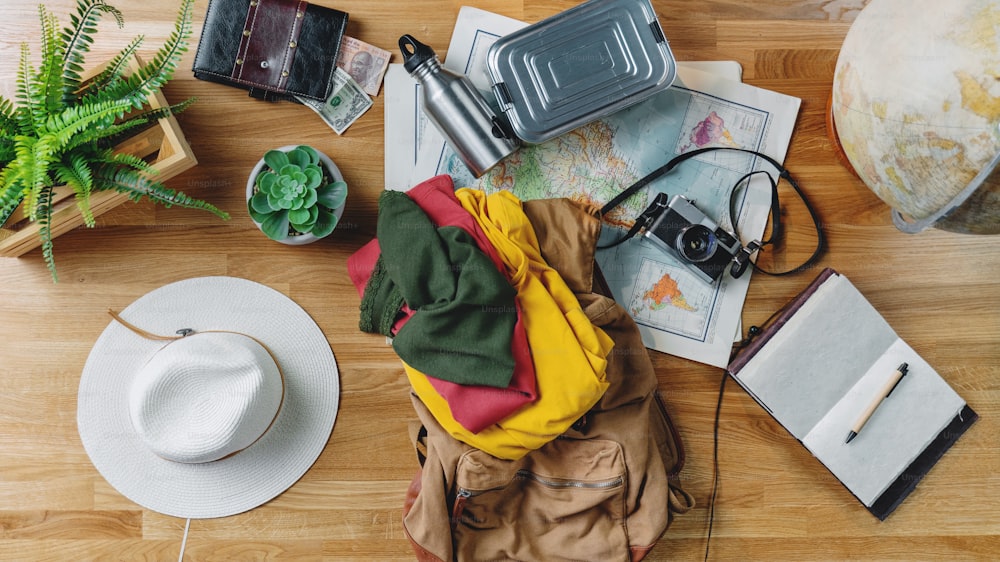 A flat lay top view desktop with maps and other travel essentials, packing and travel concept.
