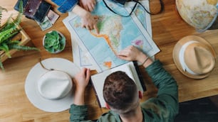 Vista superior de una pareja joven irreconocible con mapas que planifican el viaje de vacaciones, concepto de viaje de escritorio.