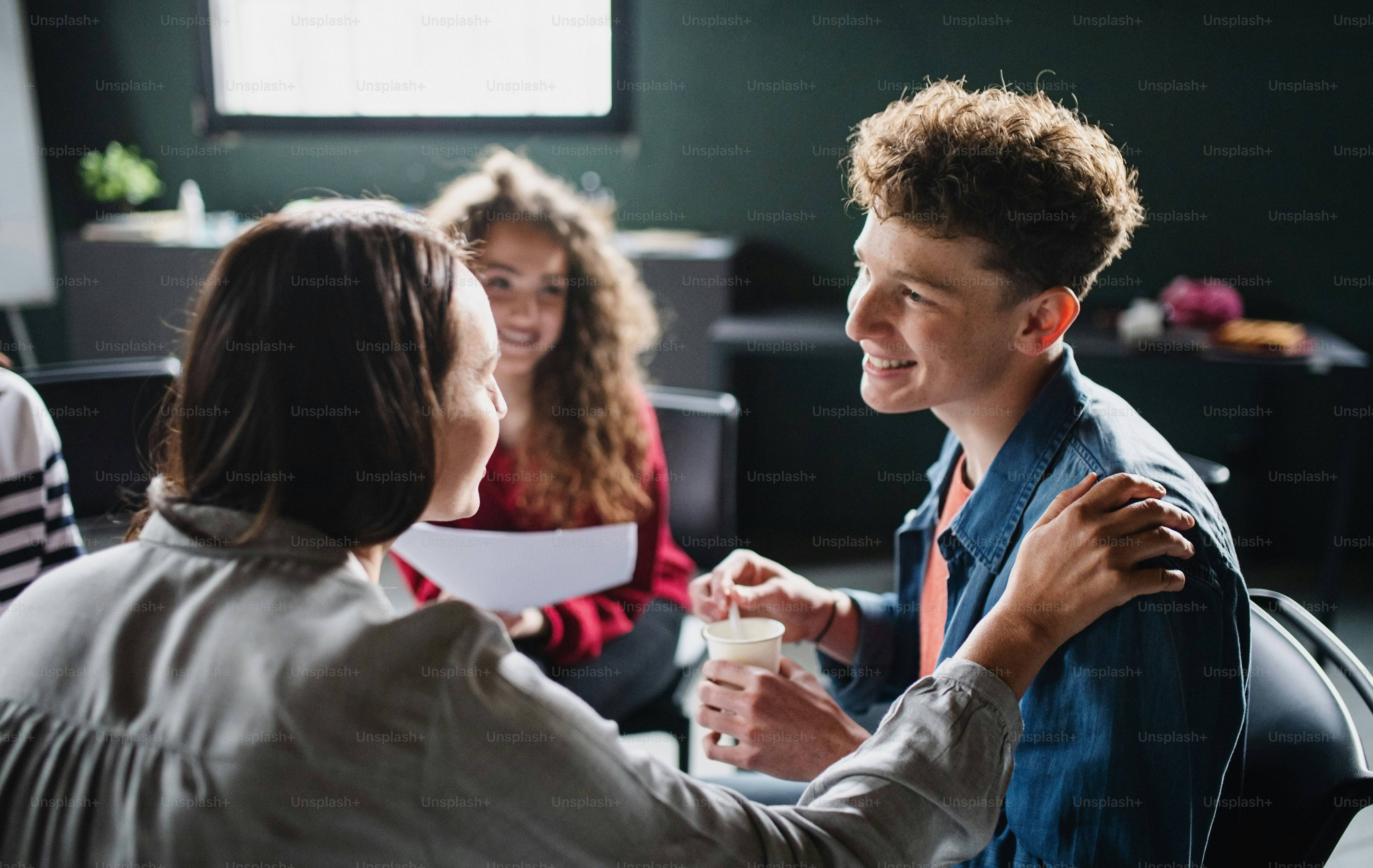 Happy men and women sitting in a circle during group therapy, talking.