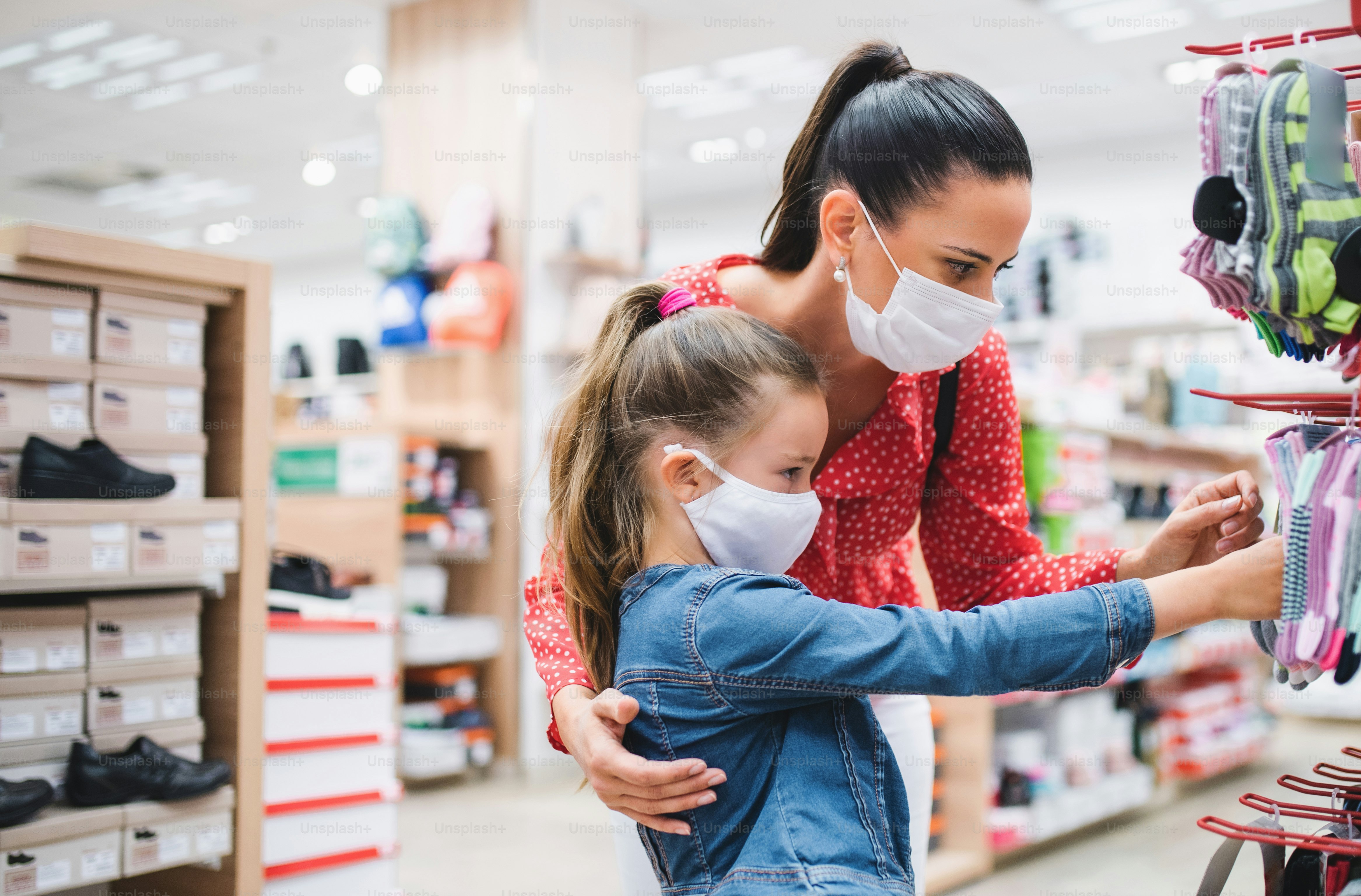 Madre e hija pequeña con mascarilla de compras en el concepto de coronavirus de zapato.