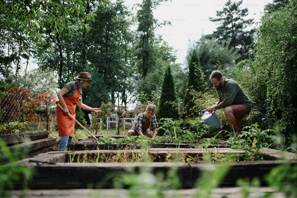Happy young and old farmers working with garden tools outdoors at a community farm.