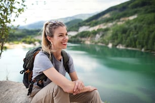 여름 휴가에 하이킹 여행을 떠나 호수에서 쉬고 있는 중년 여성 ��관광객.