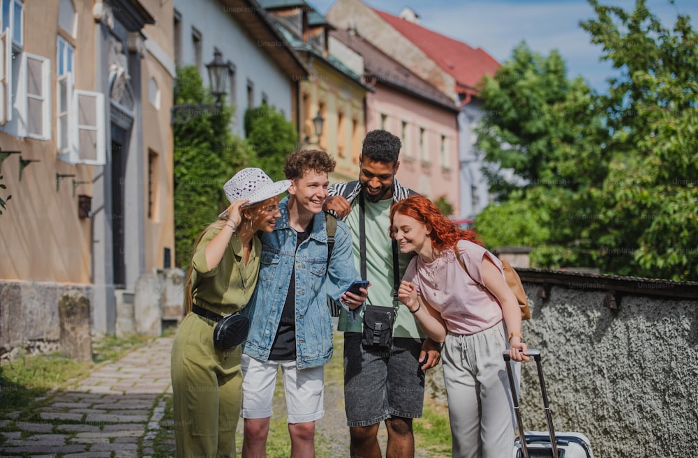 Ritratto di gruppo di giovani all'aperto in viaggio in città, utilizzando la mappa online su smartphone.