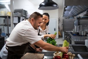 Chefs preparing vegetables for cutting in a commercial kitchen.
