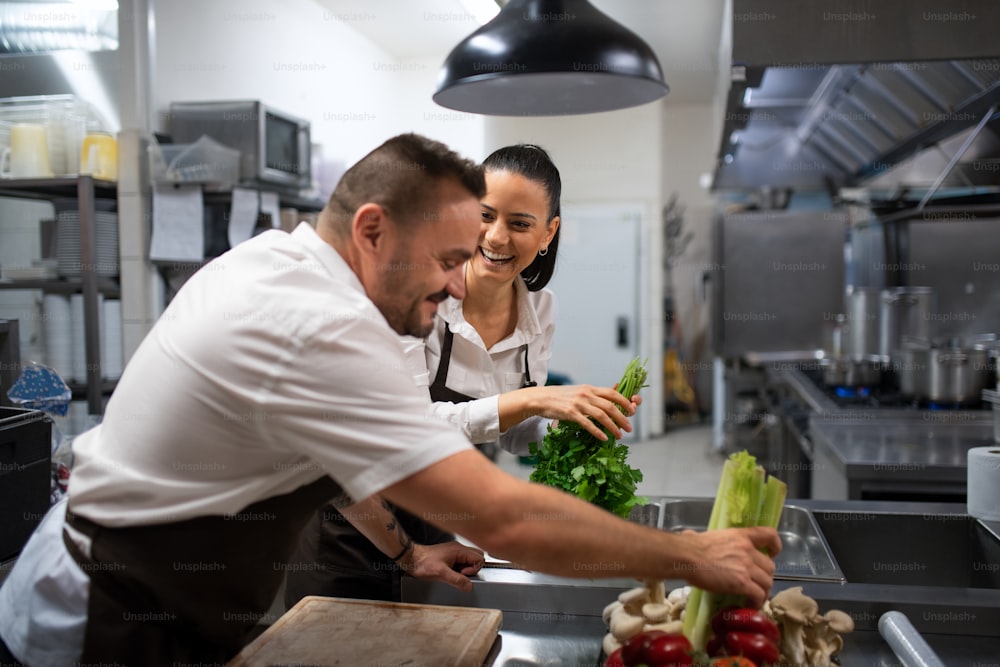 Chefs preparing vegetables for cutting in a commercial kitchen.