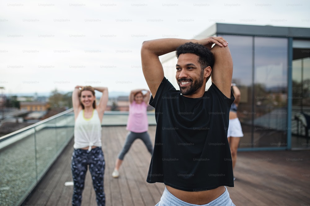 Un grupo de jóvenes haciendo ejercicio al aire libre en terraza, deporte y concepto de estilo de vida saludable.