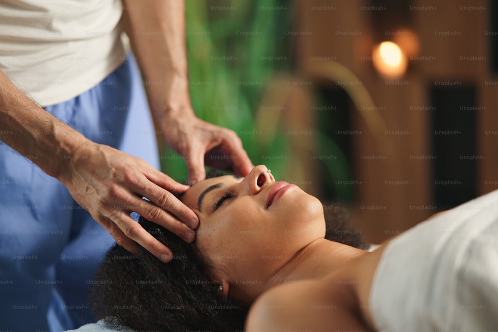 Una giovane donna che fa un massaggio rilassante alla testa presso la spa.