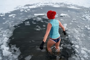 Rear view of an active senior woman in swimsuit outdoors in winter, cold therapy concept.