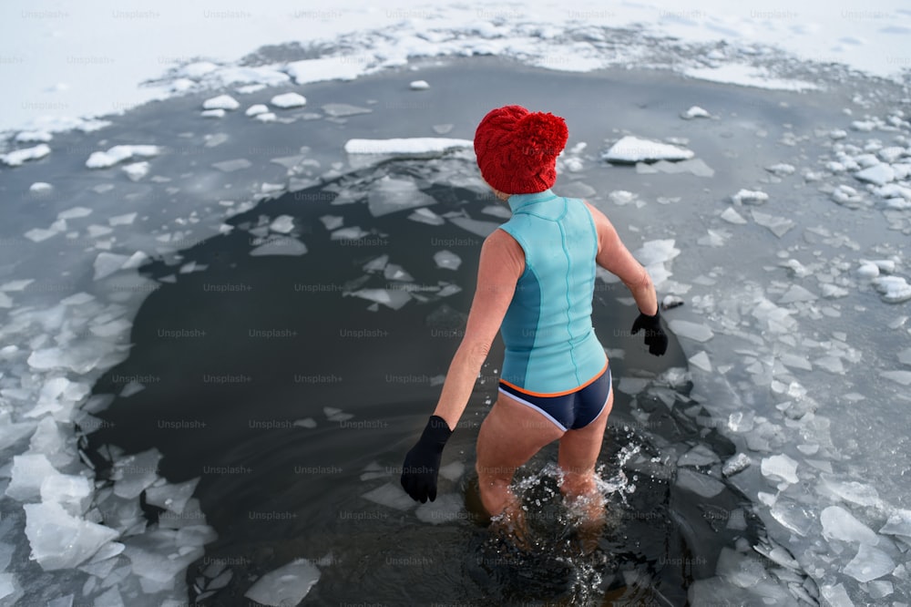 冬の屋外で水着を着たアクティブなシニア女性の後ろ姿、風邪療法のコンセプト。