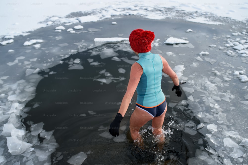 Rear view of an active senior woman in swimsuit outdoors in winter, cold therapy concept.