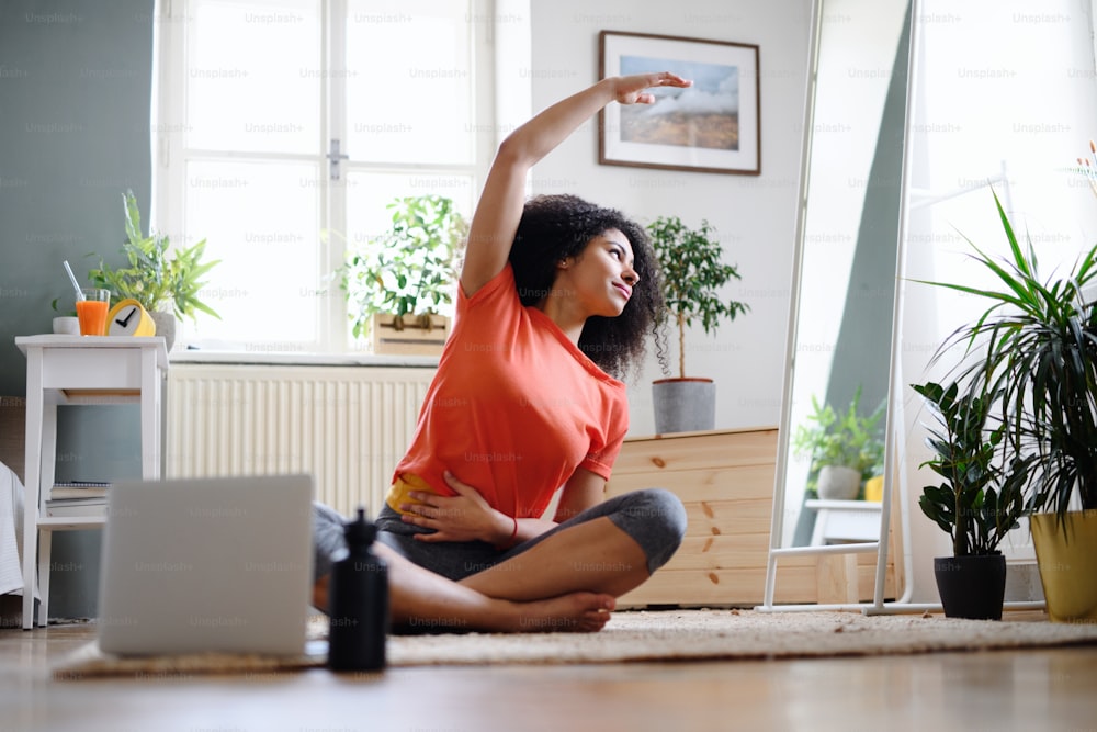 Happy young woman indoors at home, doing exercise. Sport concept.