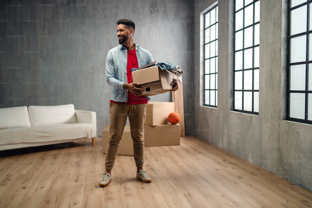 Un joven feliz sosteniendo cajas de embalaje que se trasladan a casa, nuevo concepto de vida.