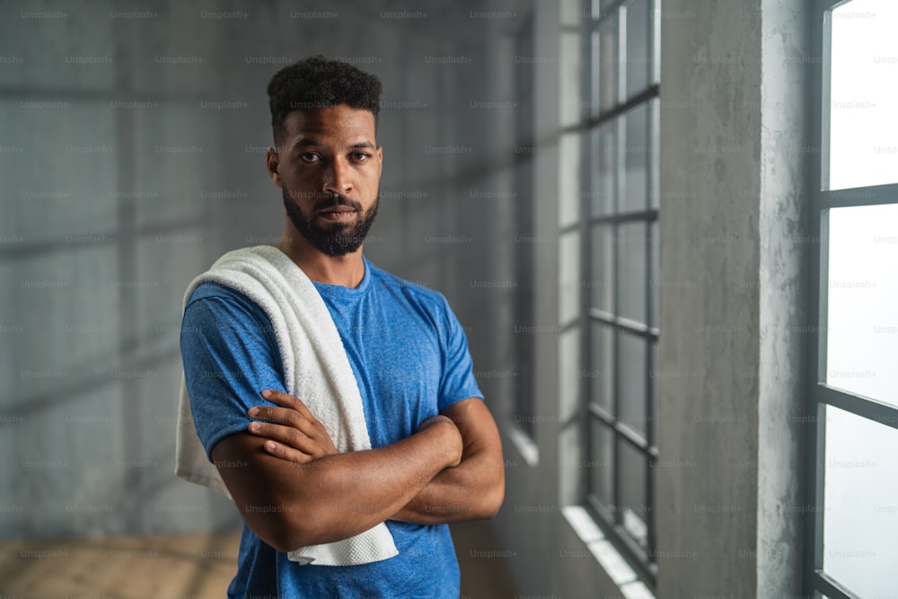 Young African American sportsman standing indoors at a gym, looking at camera, workout training concept.