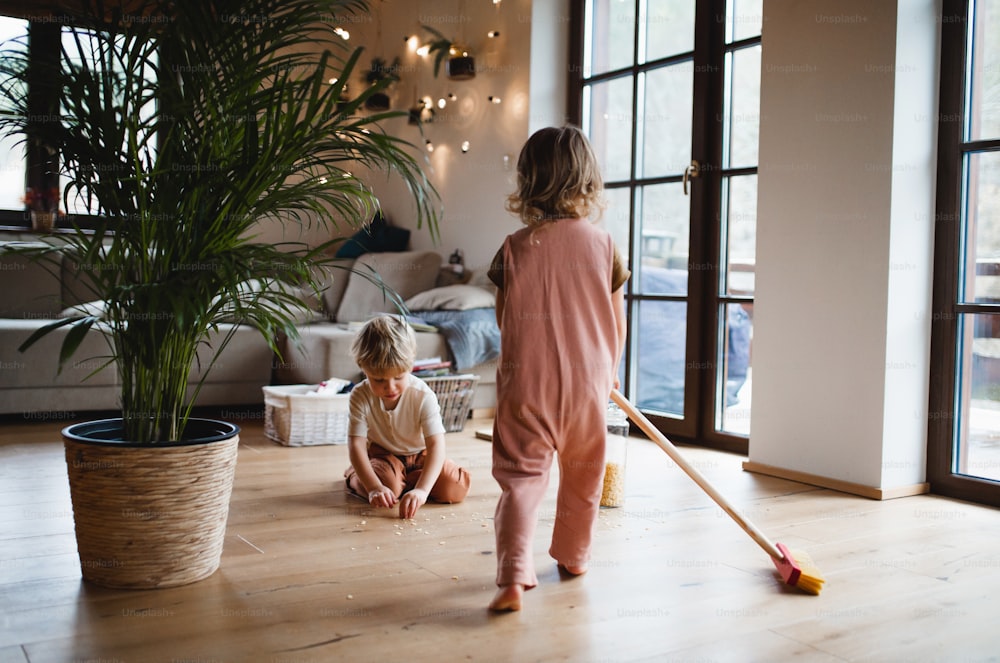 집에서 쓸고 있는 두 명의 어린 아이, 일상적인 집안일 개념.