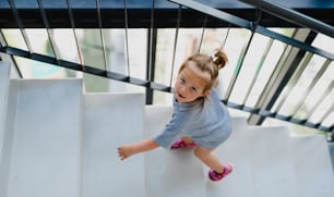 Ein hoher Winkel Blick auf das kleine Mädchen, das drinnen die Treppe hinaufgeht.