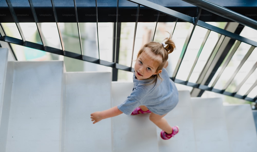 A high angle view of little girl walking up the stairs indoors.