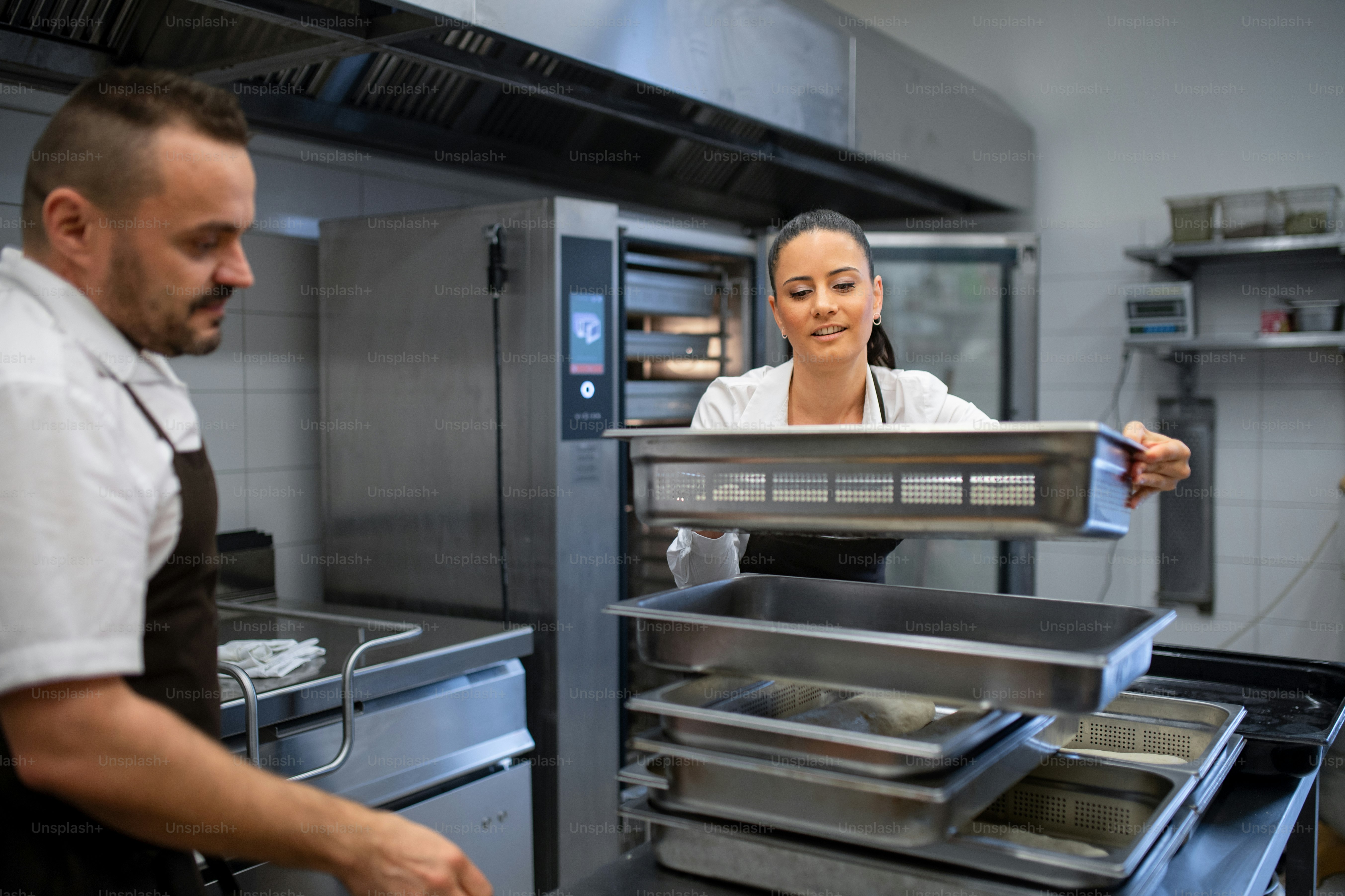 Un chef et un cuisinier travaillant sur leurs plats à l’intérieur dans
