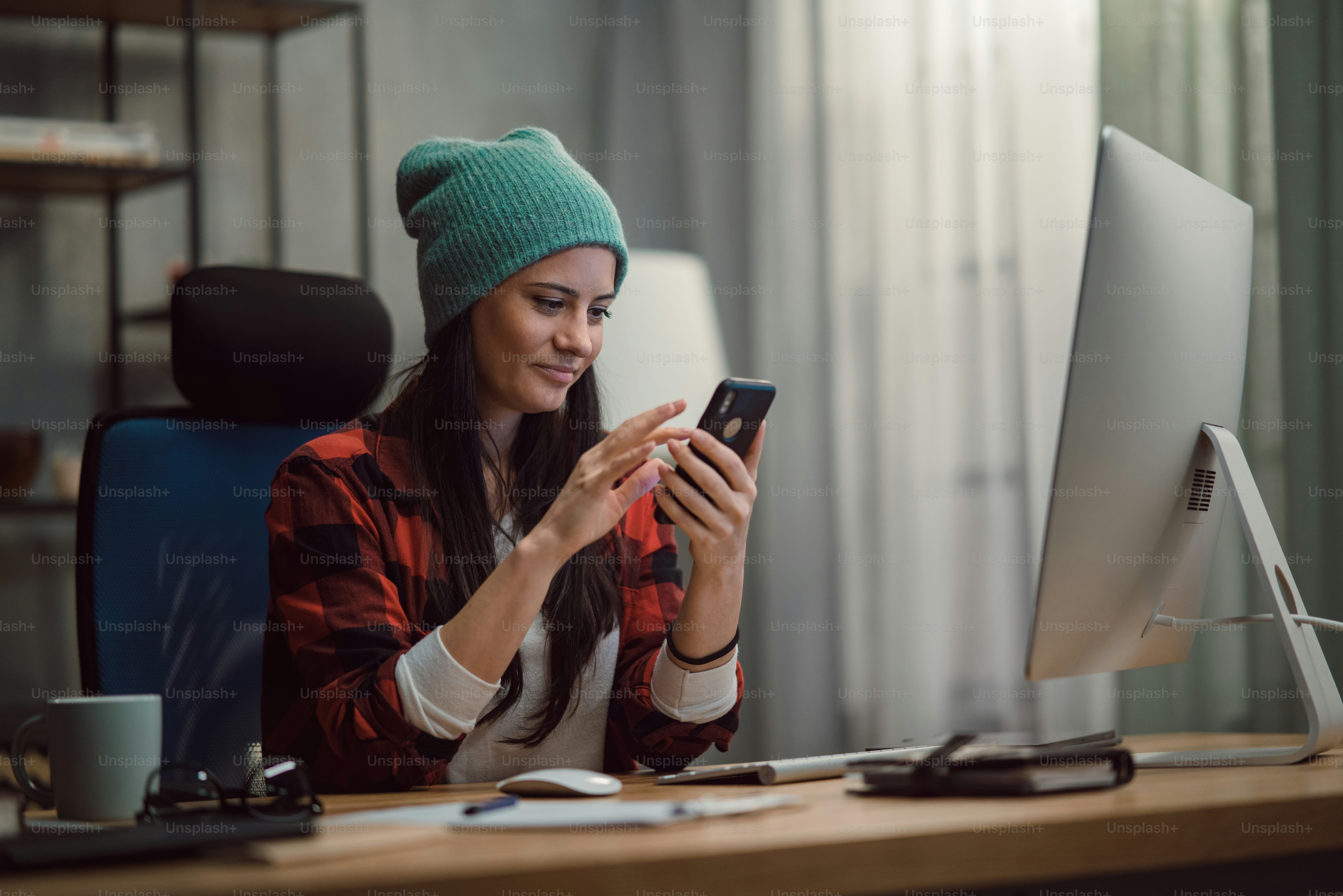 Editor video wanita yang bahagia menggunakan smartphone di dalam ruangan di studio kantor kreatif.