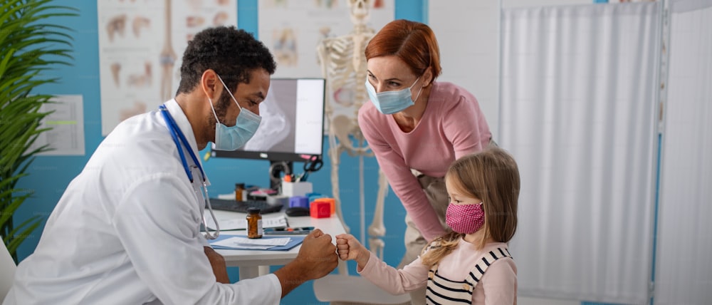 a Little girl with her mother at doctor's office on consultation, coronavirus concept.