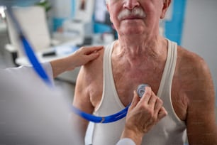A close-up of unrecognizable senior man being checked by his doctor in doctor's office.