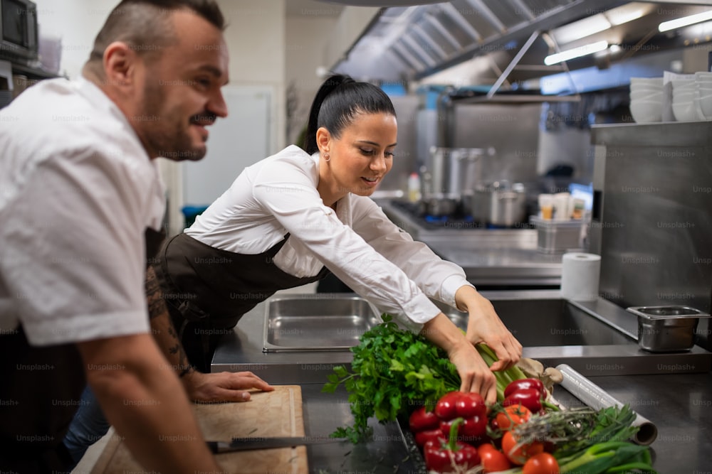 Chefs preparing vegetables for cutting in a commercial kitchen.