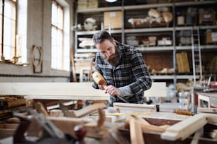 Un retrato de un carpintero maduro trabajando en su producto. Concepto de pequeña empresa.