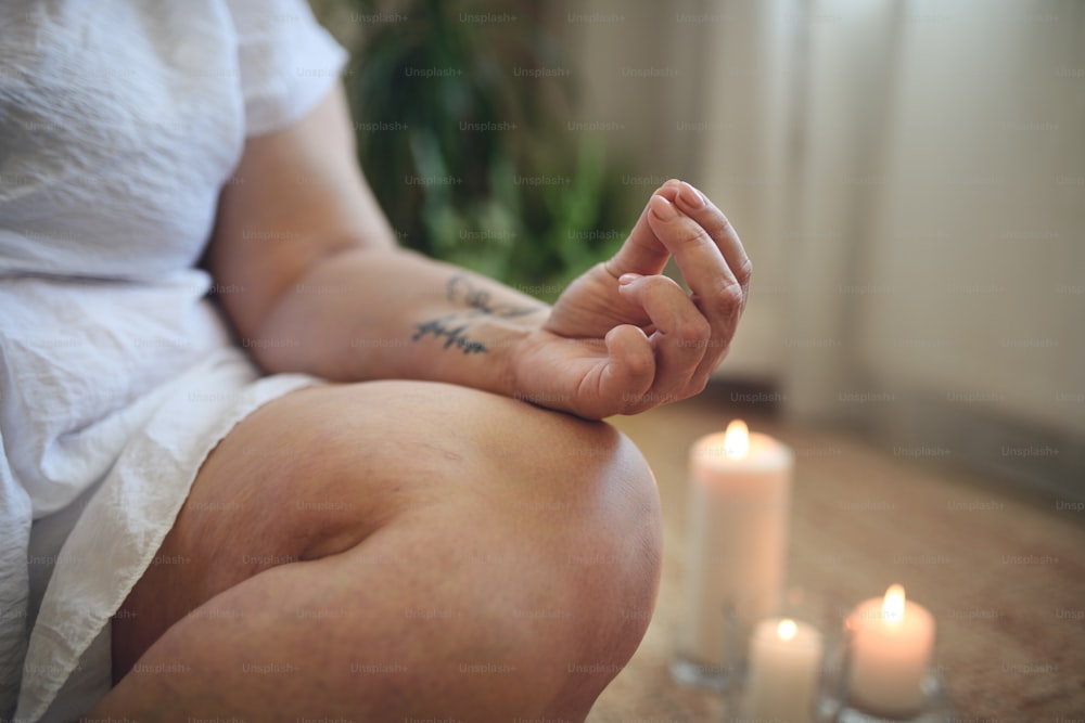 A close-up of overweight woman meditating at home.