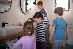 A mother with three little children in bathroom, morning routine concept.