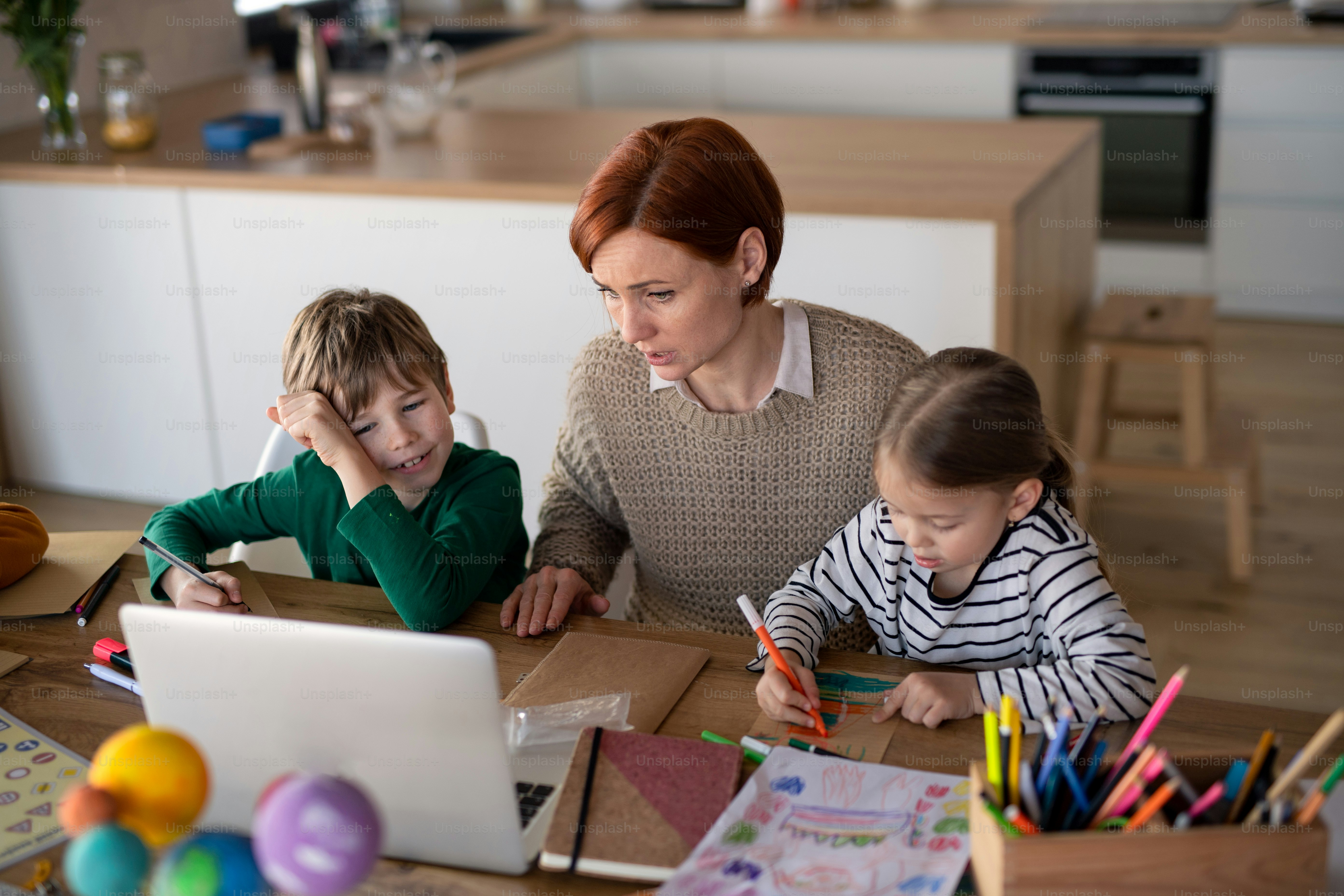 A mother of little children supervising them when distance learning and ...