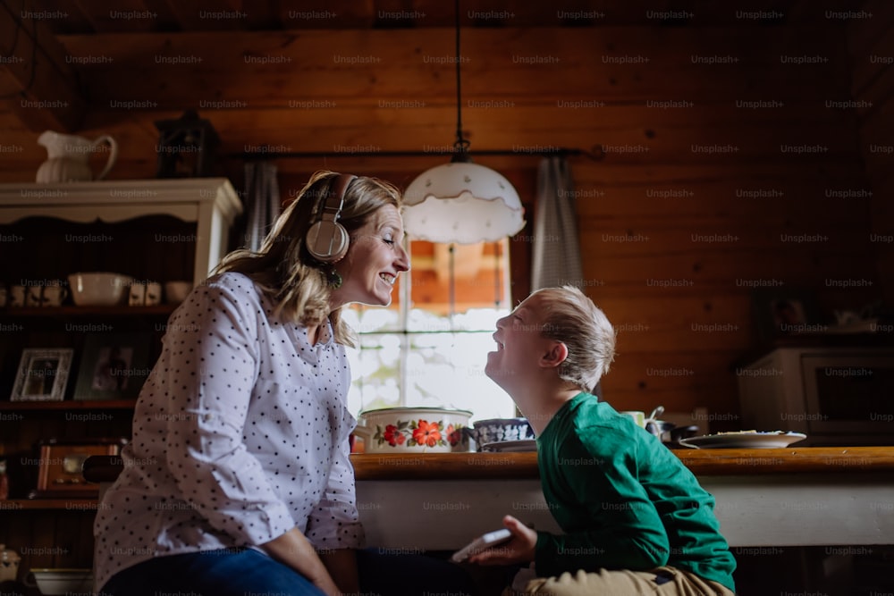 A boy with Down syndrome with his mother having lunch and using smartphone at home