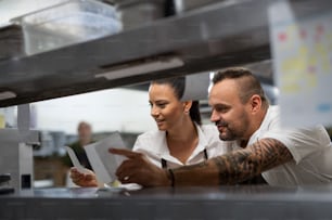 A chef and cook taking order slip in commercial kitchen.