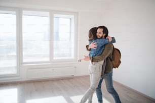 Happy young couple owners hugging in new flat, moving in, new home and relocation concept.