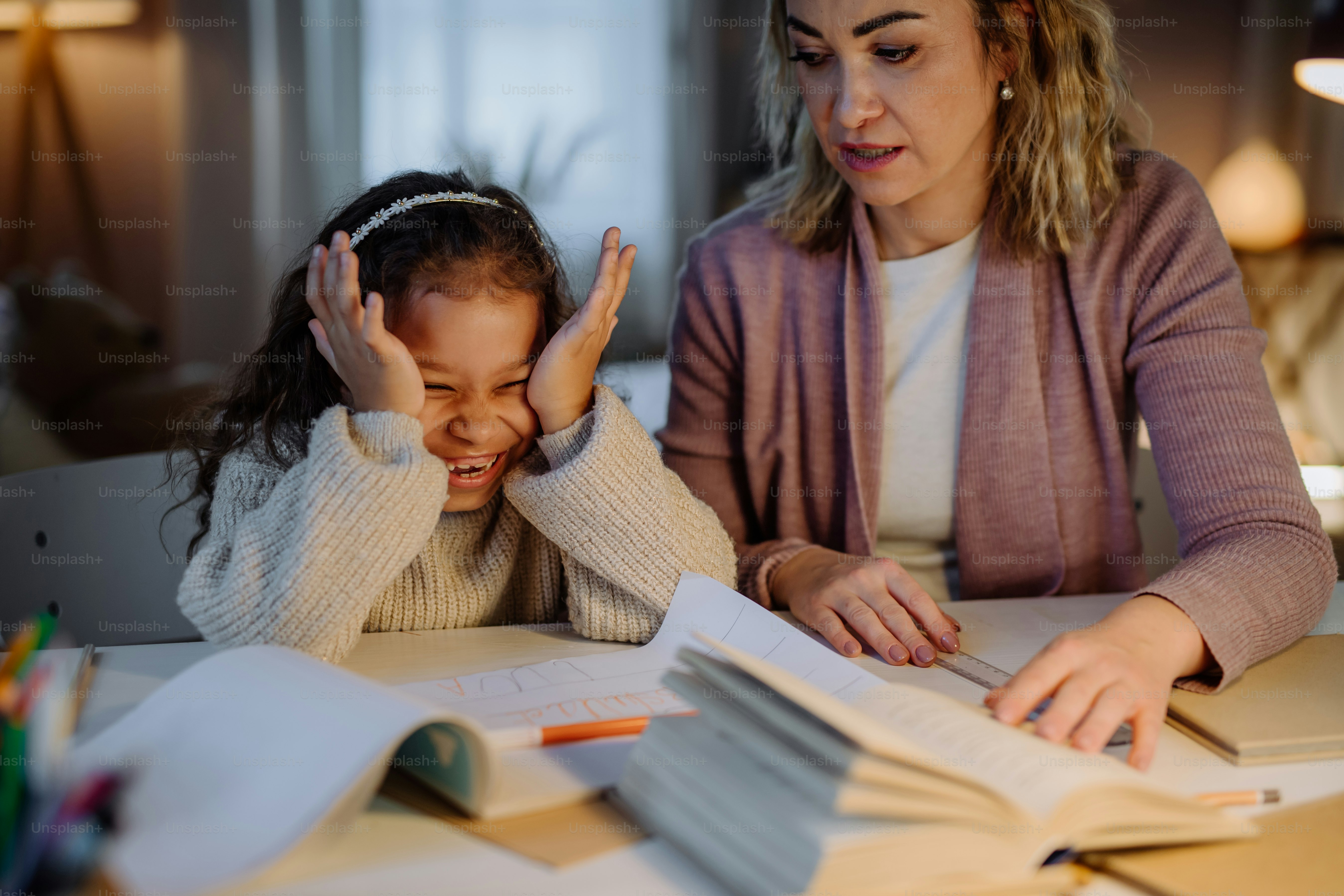 Foto Una niña feliz haciendo la tarea con su madre por la noche en casa ...