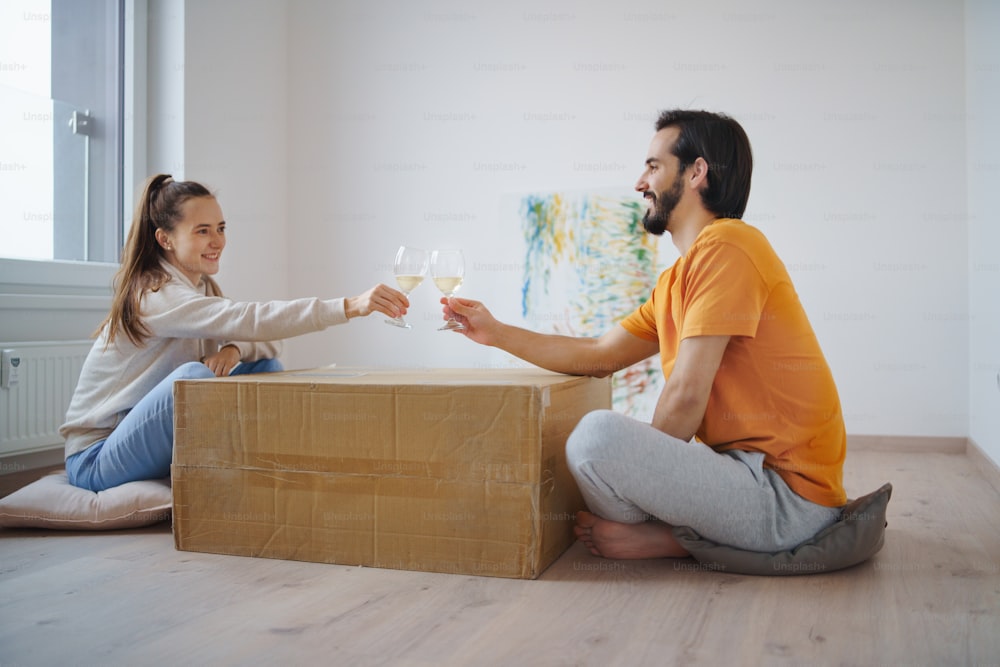 箱とワインで幸せな若いカップルは、新しいフラット、新しい家、移転のコンセプトに引っ越します。