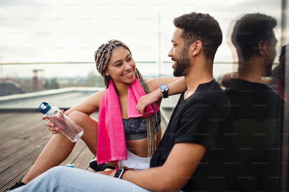 Un jeune couple se reposant après l’exercice en plein air sur la terrasse, le sport et le concept de mode de vie sain.