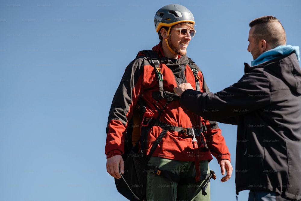 Un homme aide un pilote de parapente à se préparer au vol.