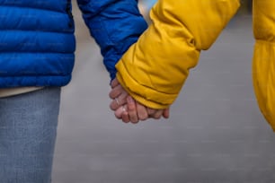A close-up of young couple holding hands, Ukrainian war and peace concept.