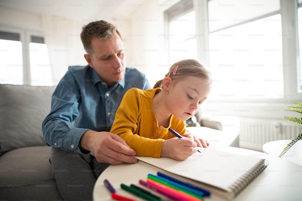 ダウン症の幼い娘を連れた父親が自宅で学習している。