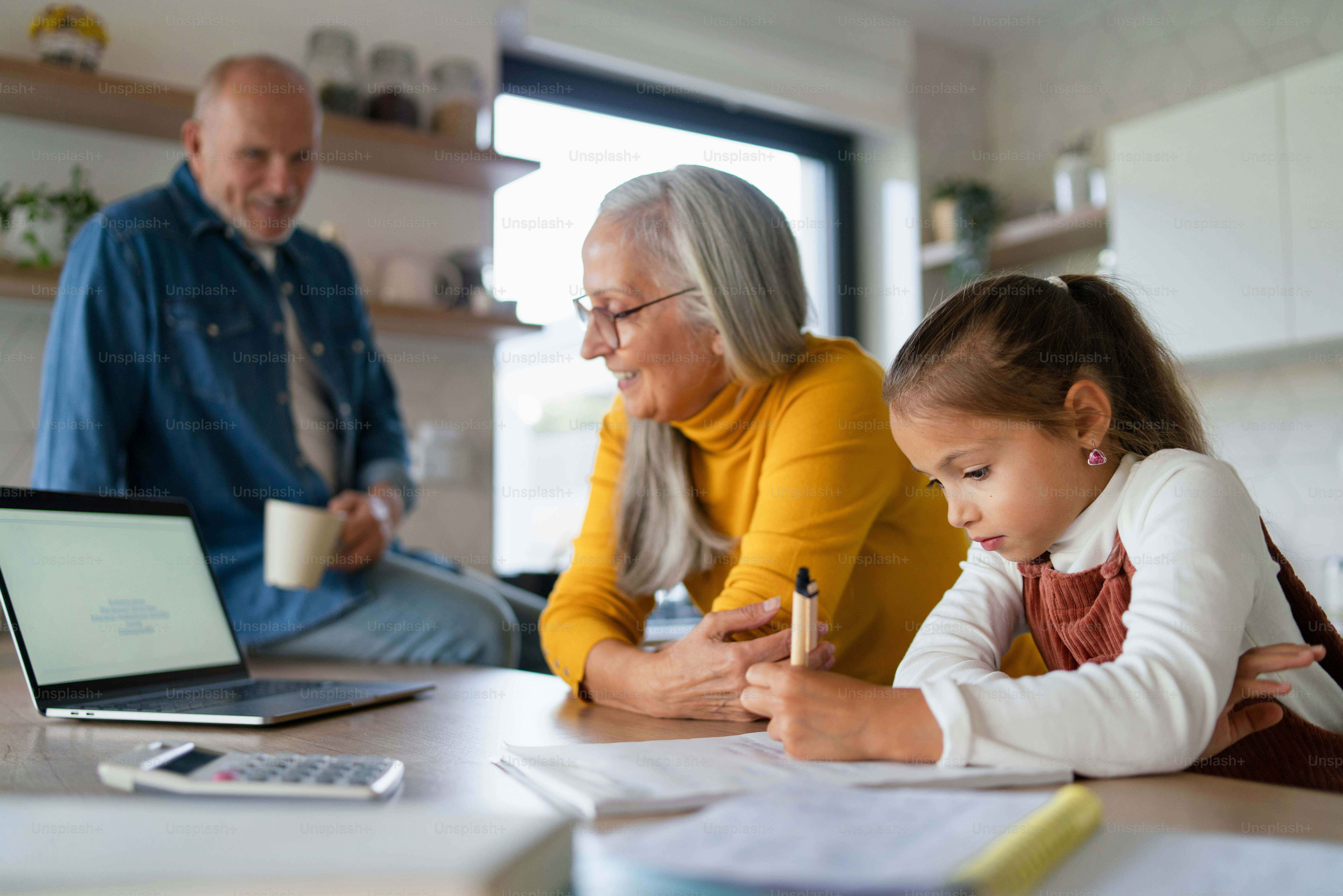 A small girl with senior grandmother doing homework at home. photo ...