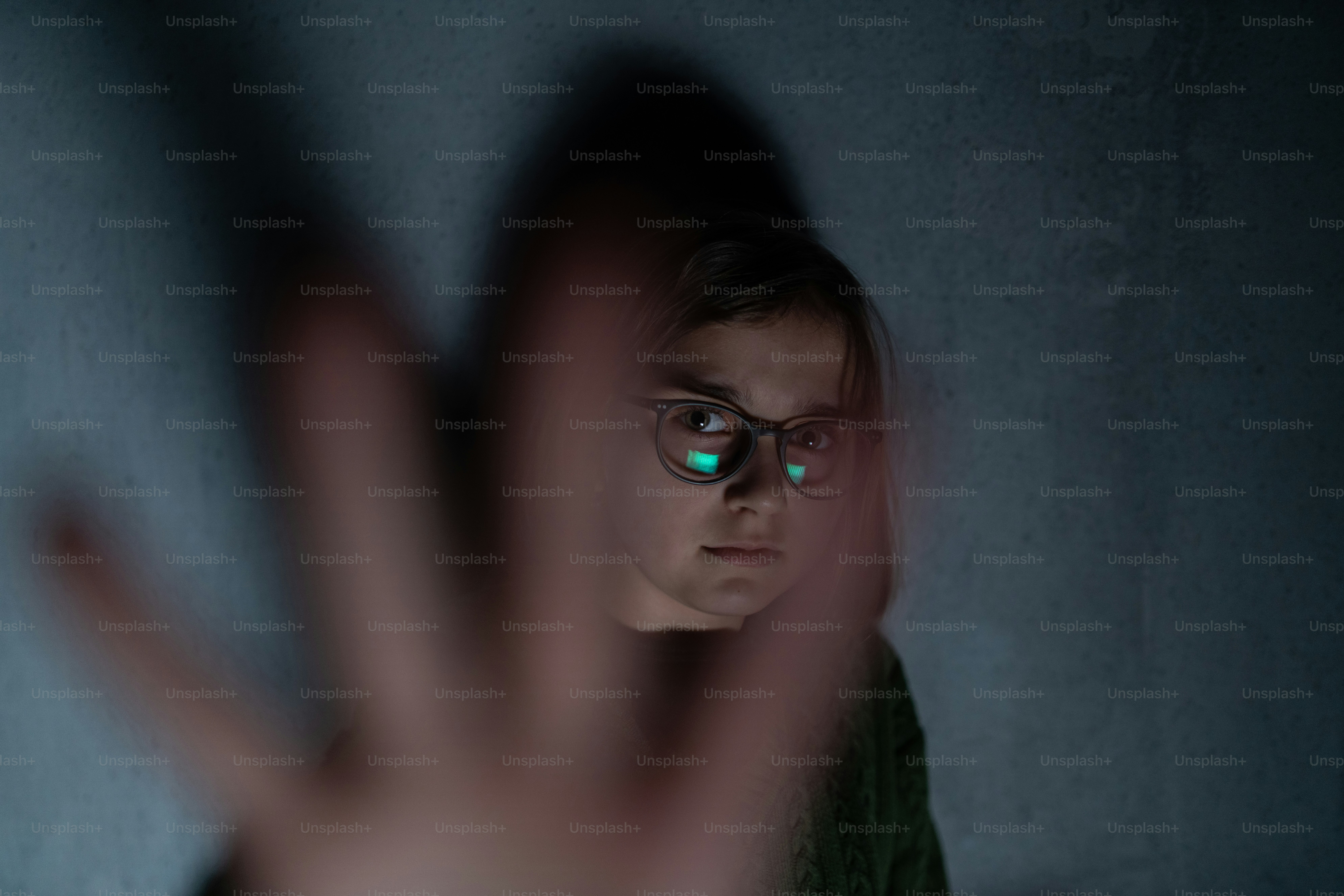 A depressed little girl, alone in darkness, looking at camera, stop the war concept.